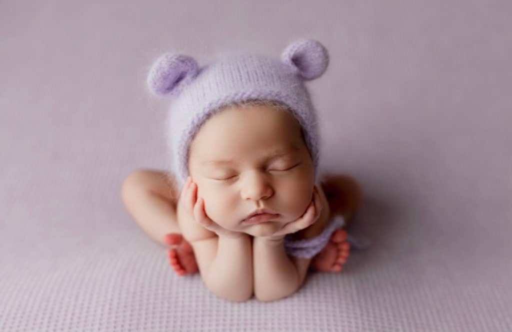 baby girl wearing purple cap. special newborn photos taken during pandemic